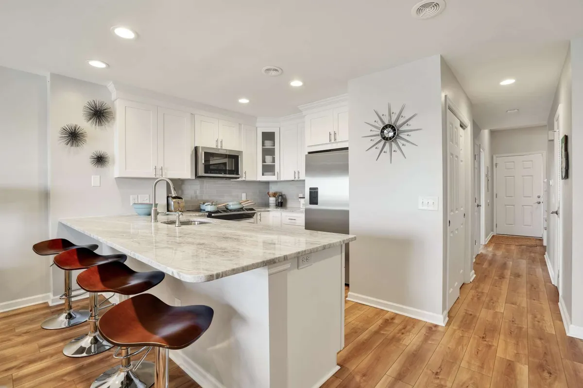 A contemporary kitchen with a large island, bar stools, and sleek stainless steel appliances. The space is designed for both cooking and socializing, featuring granite countertops and plenty of room for group gatherings or meal prep.