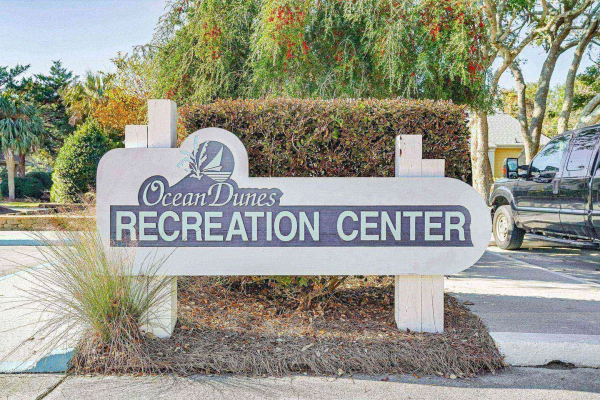 This image features the Recreation Center sign surrounded by lush vegetation and a parking area, representing the nearby community amenities available for guests. It evokes a sense of convenience and variety in activities just a short walk from the condo.