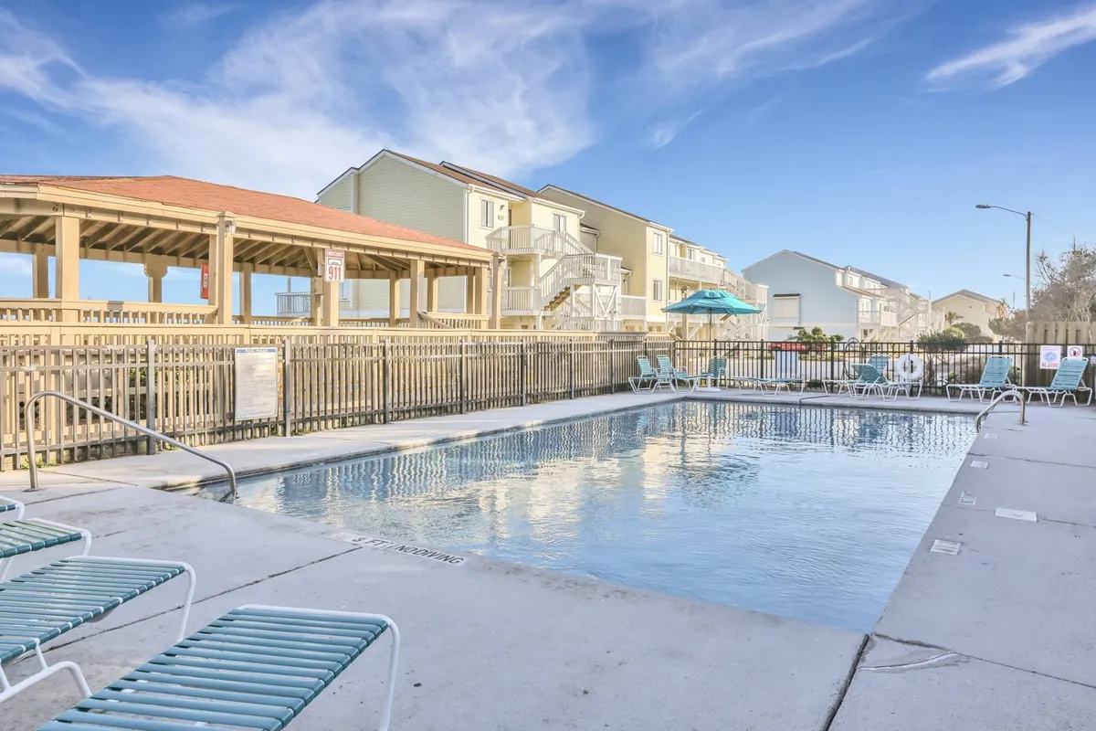 This image showcases an inviting outdoor swimming pool surrounded by lounge chairs and a covered gazebo, all set within a relaxed and social atmosphere. The pool is central, with space for sunbathing and evening gatherings, echoing the community-focused leisure theme.