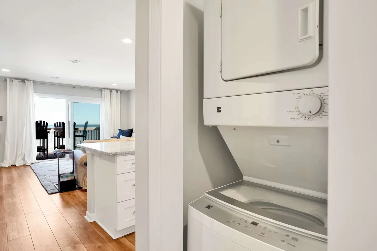 A welcoming kitchen island set near a washer and dryer, with a window view and bar stools, suggesting a multifunctional space where cooking, casual conversations, and daily routines blend seamlessly.