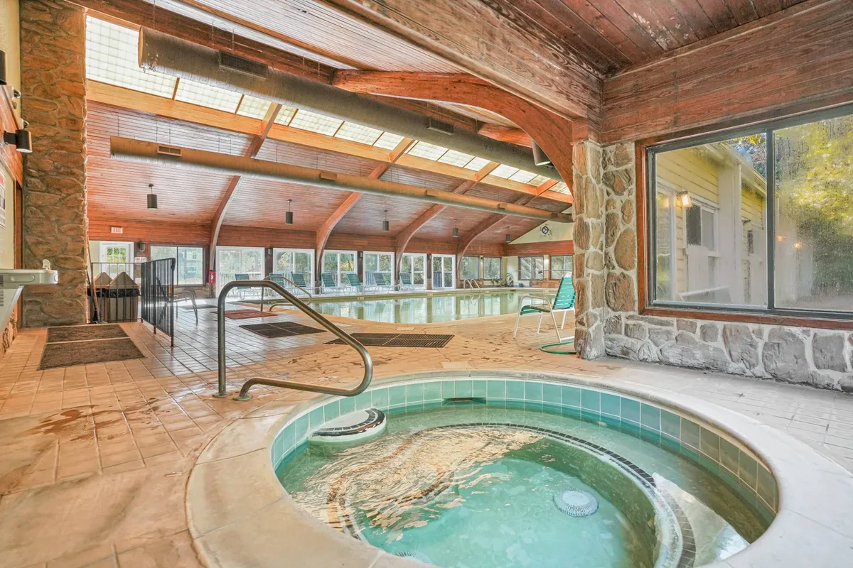 This image highlights the spa hot tub and indoor swimming pool, framed by large windows and wooden beams. The scene suggests both physical wellness and relaxation, ideal for unwinding after a day of activities or enjoying a morning workout followed by a soothing spa session.